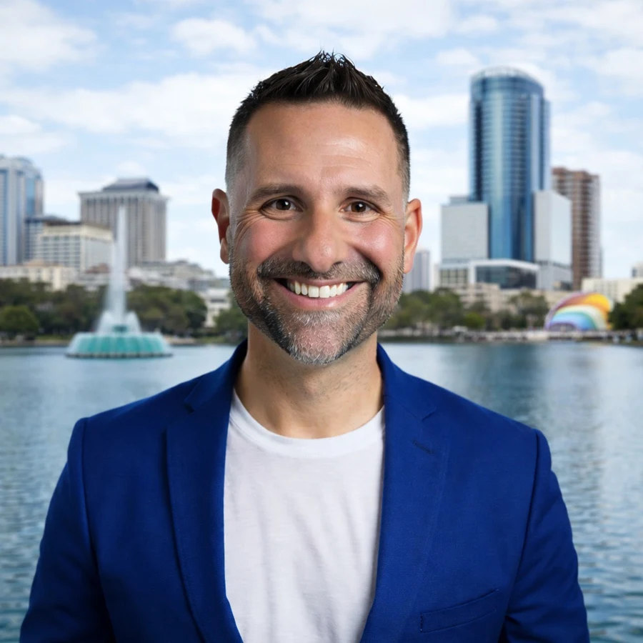 Joseph Schaefer smiling in a blue blazer and white T-shirt beside a lake, with the Orlando skyline and a fountain behind him